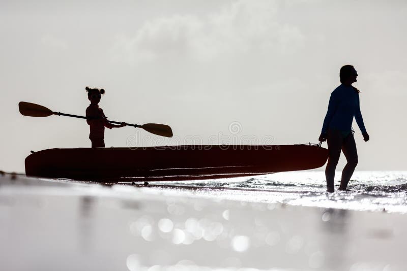 Familie, die bei Sonnenuntergang Kayak fährt lizenzfreie stockbilder Familie, die bei Sonnenuntergang Kayak fährt lizenzfreie stockbilder