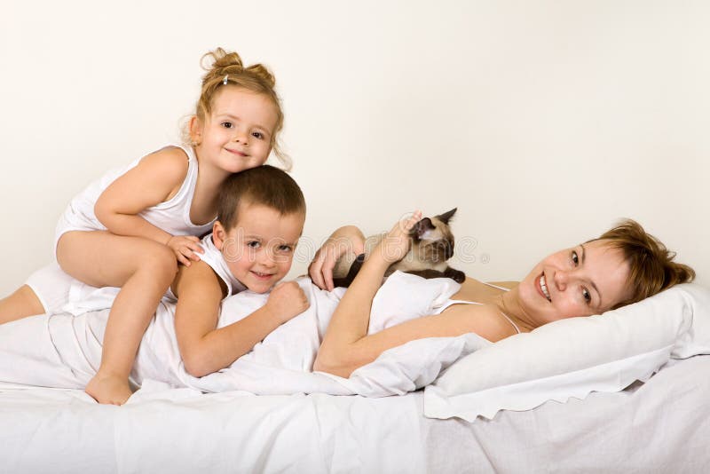 Familie, die in Bett mit ihrem kleinen Kätzchen legt stockfotos Familie, die in Bett mit ihrem kleinen Kätzchen legt stockfotos
