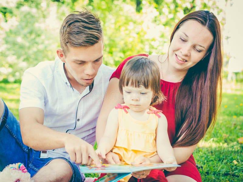 Familie die een boek lezen bij park royalty-vrije stock afbeeldingen Familie die een boek lezen bij park royalty-vrije stock afbeeldingen
