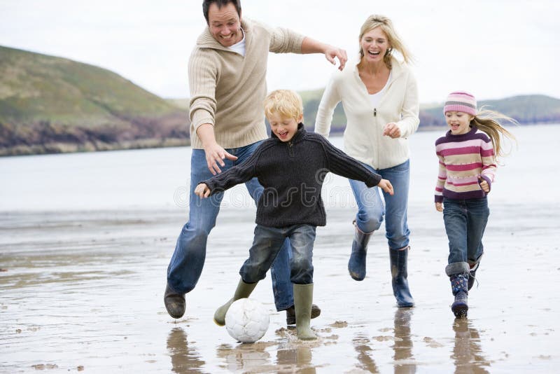 Familie, die Fußball am Strandlächeln spielt