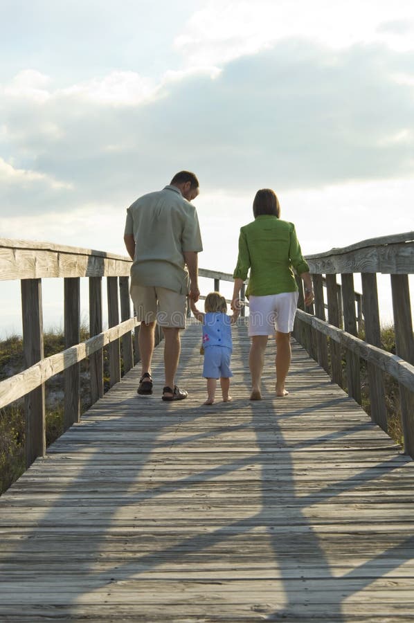 Familie, die geht auf den Strand zu setzen Familie, die geht auf den Strand zu setzen