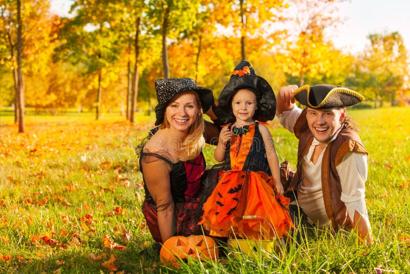 Familie die in Halloween-kostuums op het gras zitten royalty-vrije stock foto's Familie die in Halloween-kostuums op het gras zitten royalty-vrije stock foto's