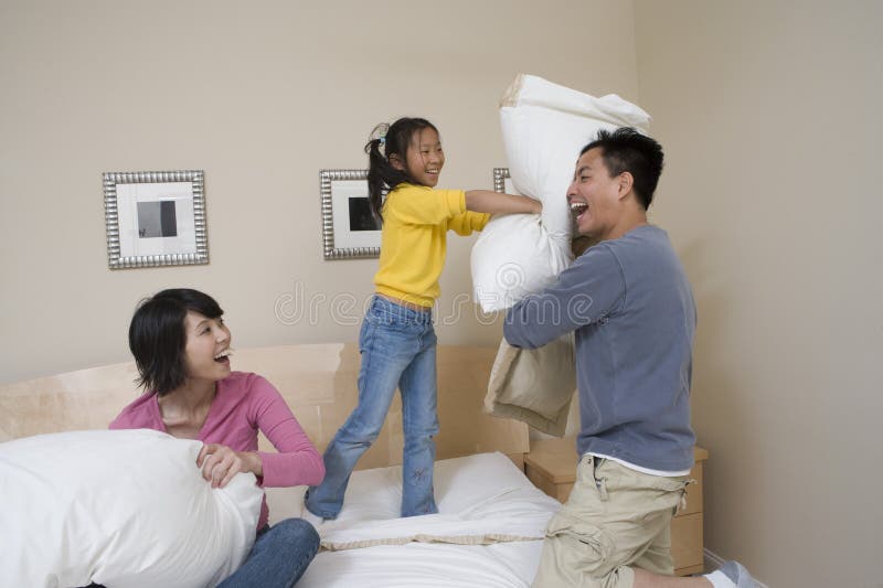 Familie die Hoofdkussenstrijd in Bed hebben stock afbeeldingen Familie die Hoofdkussenstrijd in Bed hebben stock afbeeldingen