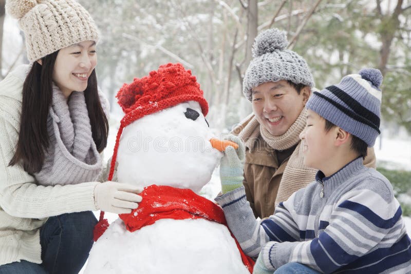 Familie die sneeuwman in een park in de winter maken