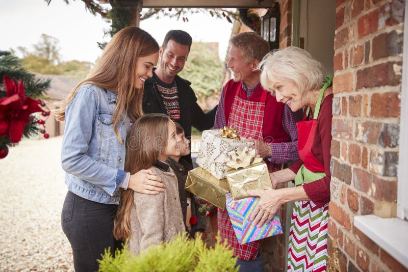 Familie, die von den Großeltern gegrüßt wird, wie sie für Besuch am Weihnachtstag mit Geschenken ankommen lizenzfreies stockbild Familie, die von den Großeltern gegrüßt wird, wie sie für Besuch am Weihnachtstag mit Geschenken ankommen lizenzfreies stockbild