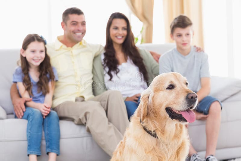 Happy family and dog watching TV together in living room. Happy family and dog watching TV together in living room