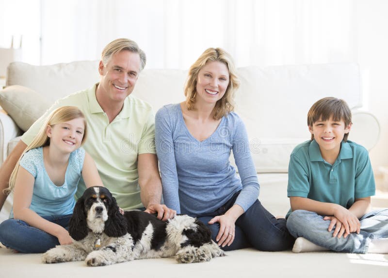 Familie mit dem Schoßhund, der auf Boden im Wohnzimmer sitzt