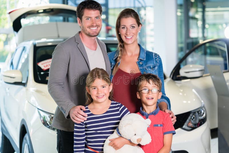 Family with children buying new car at auto dealership, mom, dad and kids standing in showroom. Family with children buying new car at auto dealership, mom, dad and kids standing in showroom