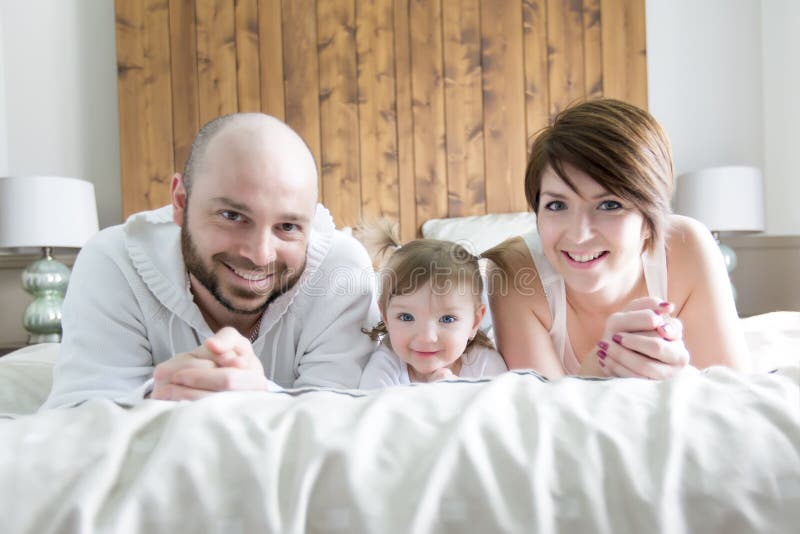Familie mit Kind Glückliche Eltern, die mit Baby auf Bett spielen lizenzfreies stockbild Familie mit Kind Glückliche Eltern, die mit Baby auf Bett spielen lizenzfreies stockbild