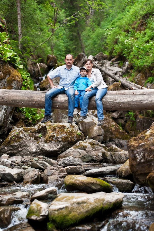 Familie pe un copac căzut peste râu stock image