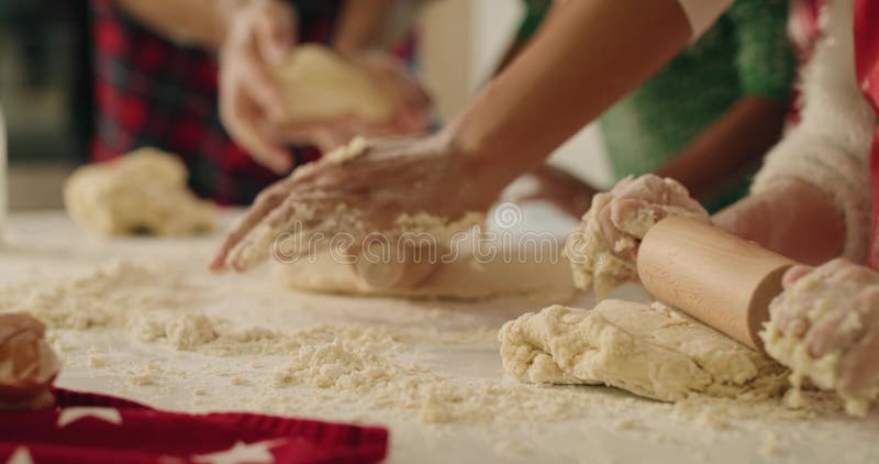 Familie rollt den Teig für Weihnachtskekse