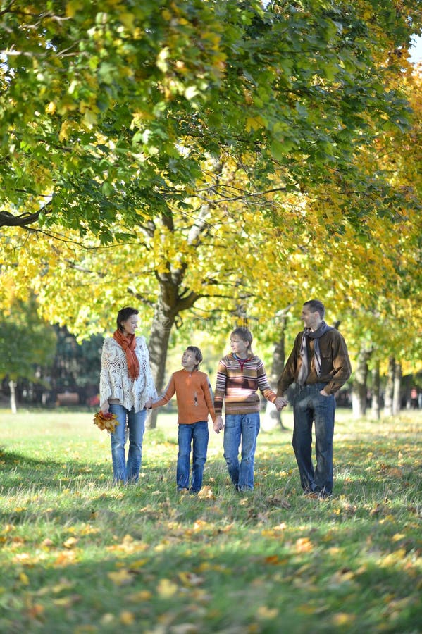 Familie van vier die in de herfstpark lopen stock afbeeldingen Familie van vier die in de herfstpark lopen stock afbeeldingen