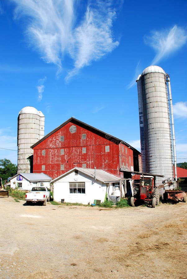 Family farm, with red barn, two silos, and assorted farm equipment, all under a bright blue sky. Barn built in 1872. Located in rural Pennsylvania. Family farm, with red barn, two silos, and assorted farm equipment, all under a bright blue sky. Barn built in 1872. Located in rural Pennsylvania.