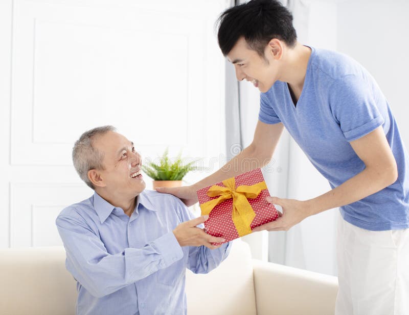 Familienfeiern und -sohn Geschenk gebend dem Vater lizenzfreie stockfotografie Familienfeiern und -sohn Geschenk gebend dem Vater lizenzfreie stockfotografie