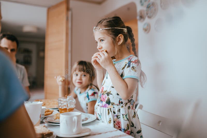 Familienfrühstück zu Hause in der netten gemütlichen Küche Mutter, Vater und ihre zwei Töchter, die Pfannkuchen essen lizenzfreie stockfotos Familienfrühstück zu Hause in der netten gemütlichen Küche Mutter, Vater und ihre zwei Töchter, die Pfannkuchen essen lizenzfreie stockfotos