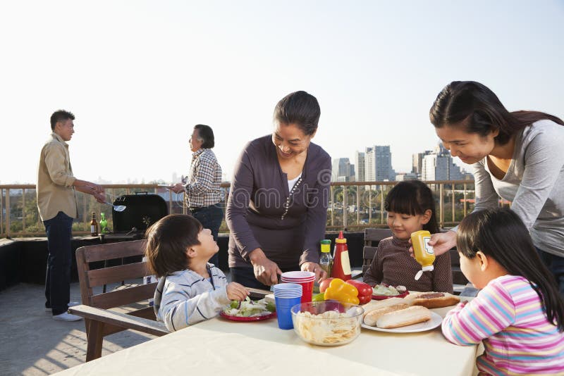 Familiengrillpartei, sitzend am Tisch lizenzfreies stockfoto Familiengrillpartei, sitzend am Tisch lizenzfreies stockfoto