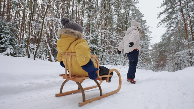 Familieweekeinde en wintervakantie in bosvrouw die haar kleine zoon in naaldbos zwaait