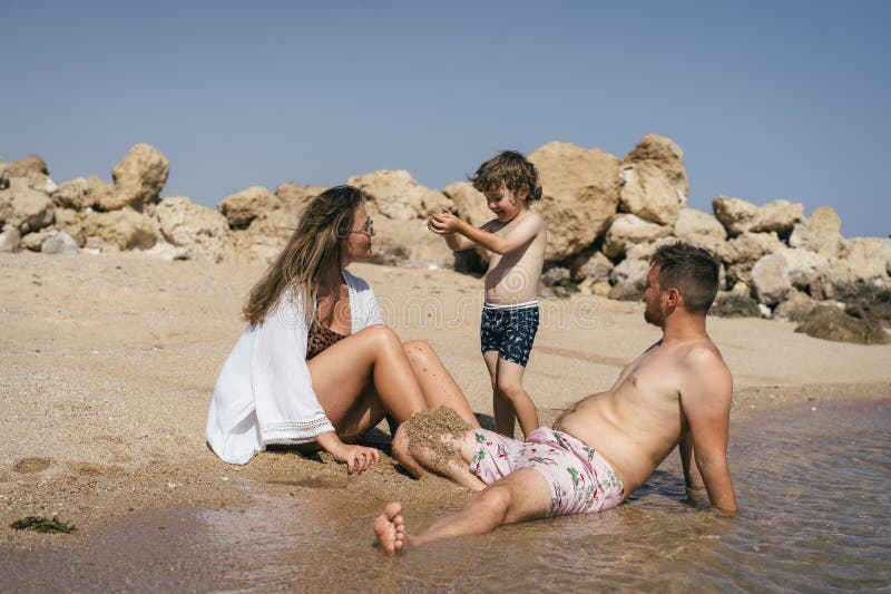 Familj leker på en sandstrand i solen royaltyfri foto