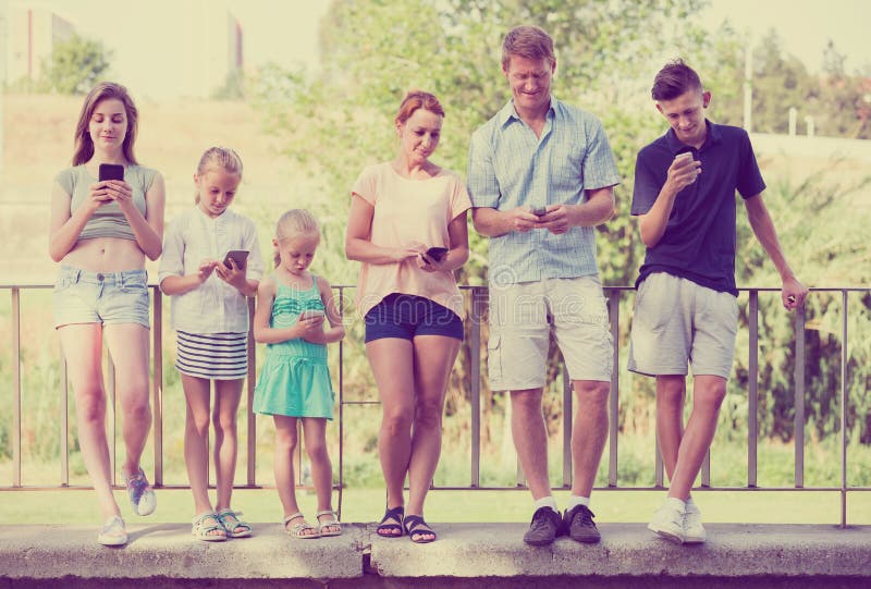 Familj med ungar som spelar med mobiltelefoner arkivfoto Familj med ungar som spelar med mobiltelefoner arkivfoto