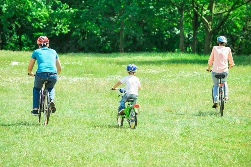 Familj som rider cykeln i parkera arkivbilder Familj som rider cykeln i parkera arkivbilder