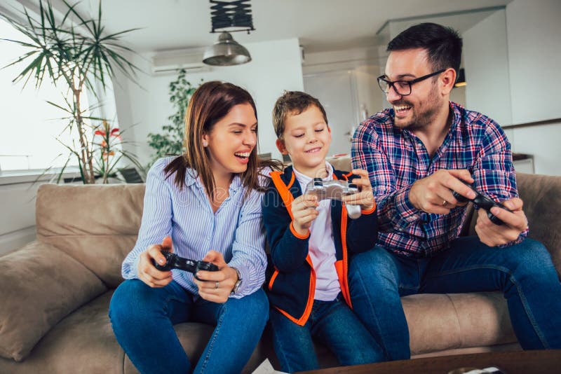 Familj som sitter p? en soffa och spelar videospel och ?ter pizza arkivbild Familj som sitter p? en soffa och spelar videospel och ?ter pizza arkivbild