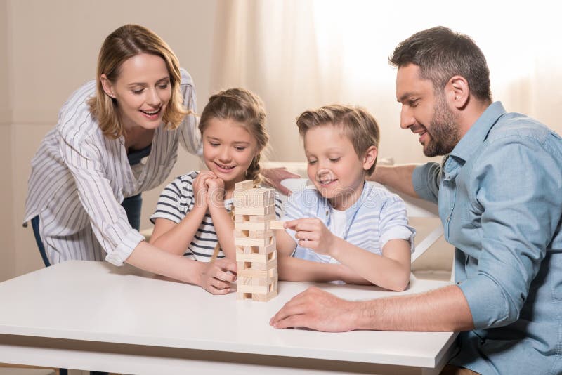 Familj som tillsammans spelar Jenga modigt hemmastatt arkivbilder Familj som tillsammans spelar Jenga modigt hemmastatt arkivbilder