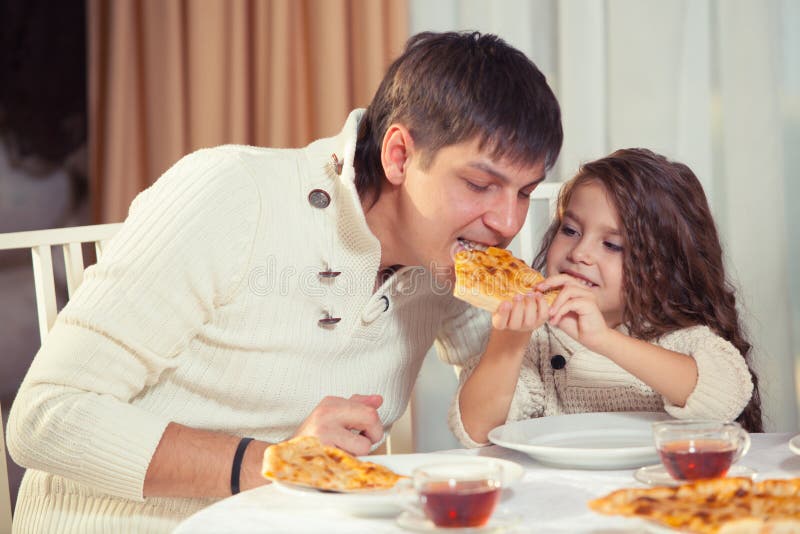 Familj som äter matställen på en äta middag tabell, rund tabell, pizza, apelsin, hus som göras av trä royaltyfri fotografi Familj som äter matställen på en äta middag tabell, rund tabell, pizza, apelsin, hus som göras av trä royaltyfri fotografi