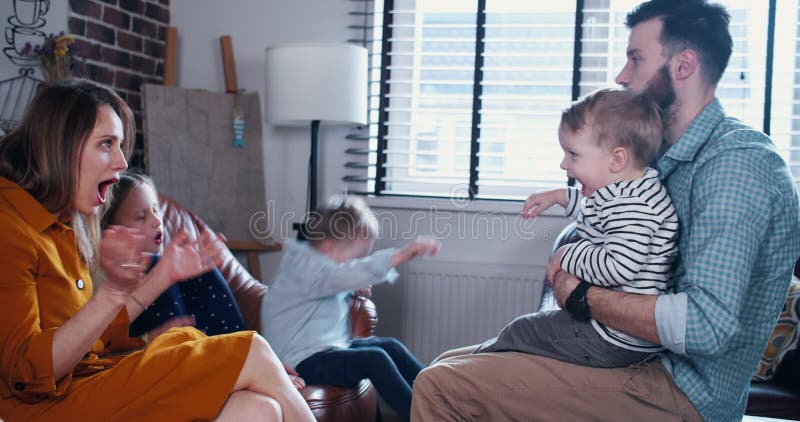 Familjerelaterat koncept: unga lyckliga, kaukasiska föräldrar leker med barn och har roligt hemma i långsam rörelse.