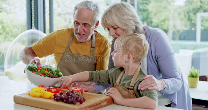 Familjesallad och mor- och farföräldrar med barn i köket för att lära sig mat och band i hemmet. Fruktfoder och arkivfilmer