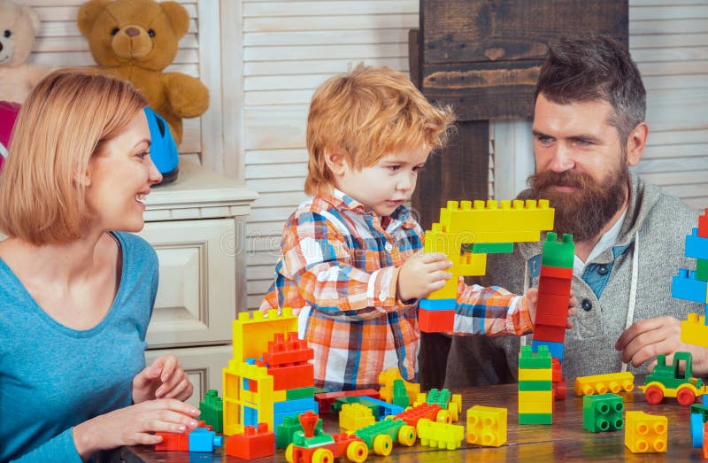 Familjespel med färgade plastbyggblock hemma. Familjespel med barn. Mor och far leker med sin son arkivbild