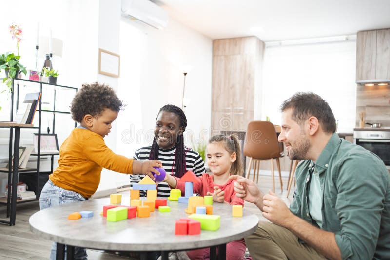 Familjeuppspelning med flera raser och färgade block i ett ljust vardagsrum arkivfoto