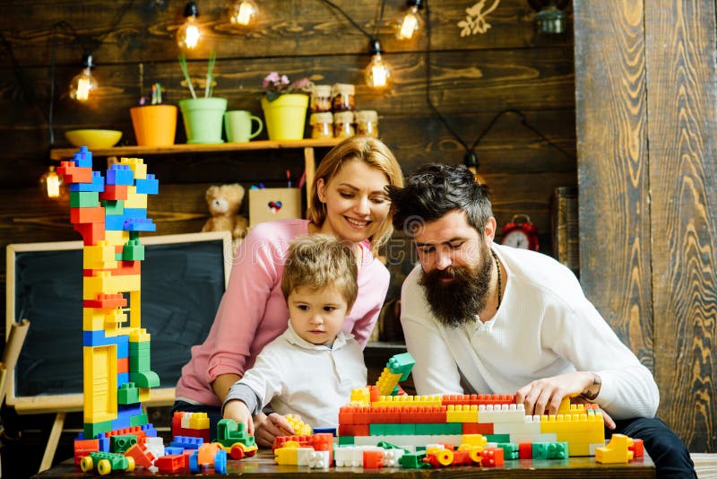 Familjeuppspelning med konstruktor hemma Fader hjälper till att bygga en vägg av leksakstegel, plastblock Mamma tittar royaltyfria foton