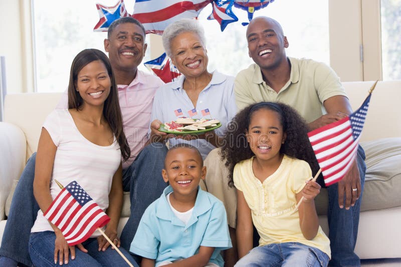 Family in living room on fourth of July with flags and cookies smiling. Family in living room on fourth of July with flags and cookies smiling