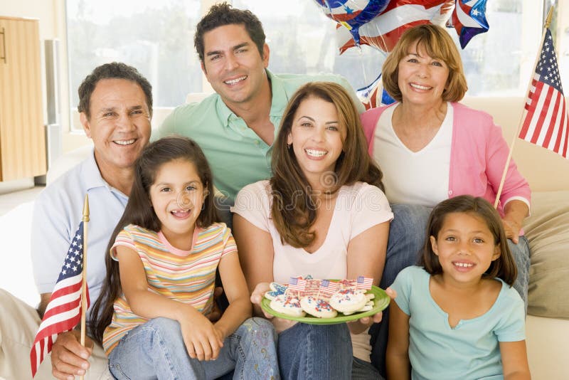 Family in living room on fourth of July with flags and cookies smiling. Family in living room on fourth of July with flags and cookies smiling