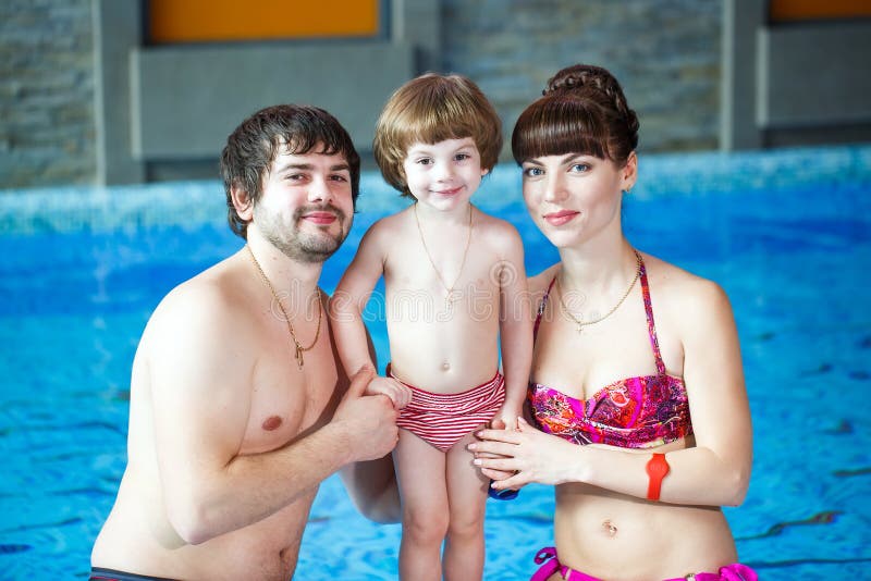 Familjsimning i p?len Den lyckliga familjen spenderar tid och kopplar av i simbassängen arkivfoto Familjsimning i p?len Den lyckliga familjen spenderar tid och kopplar av i simbassängen arkivfoto