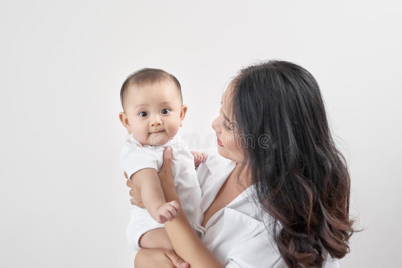 Famille affectueuse heureuse Jeune mère de sourire étreignant le bébé riant image libre de droits Famille affectueuse heureuse Jeune mère de sourire étreignant le bébé riant image libre de droits