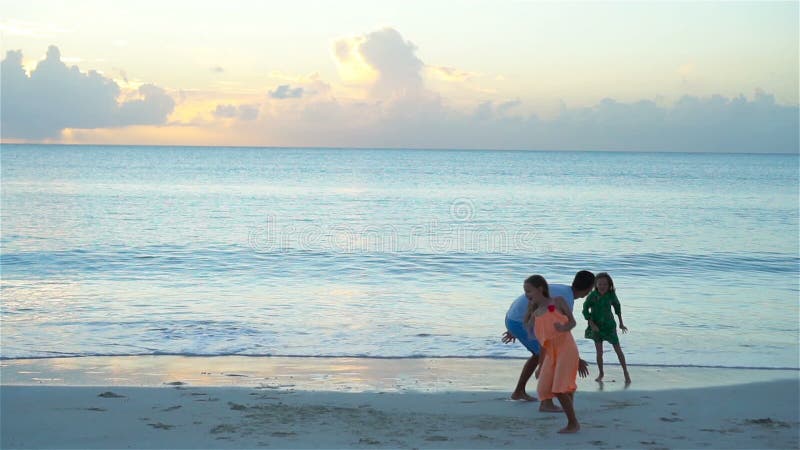 Famille appréciant le temps de plage au coucher du soleil Mouvement lent banque de vidéos