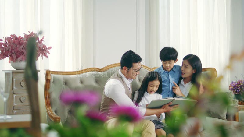 Famille asiatique avec le livre de lecture de deux enfants ensemble