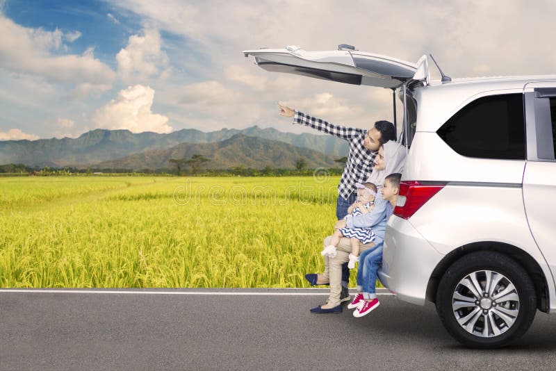 Famille asiatique s'asseyant derrière une voiture photographie stock libre de droits Famille asiatique s'asseyant derrière une voiture photographie stock libre de droits