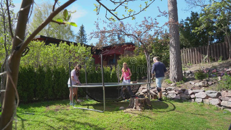 Famille assembler trampoline dans la cour pendant le printemps ensoleillé. clips vidéos