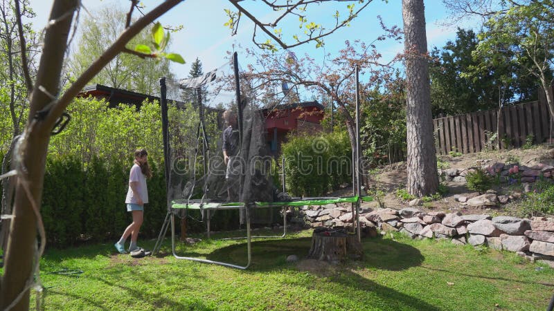 Famille assembler trampoline dans la cour pendant le printemps ensoleillé. banque de vidéos