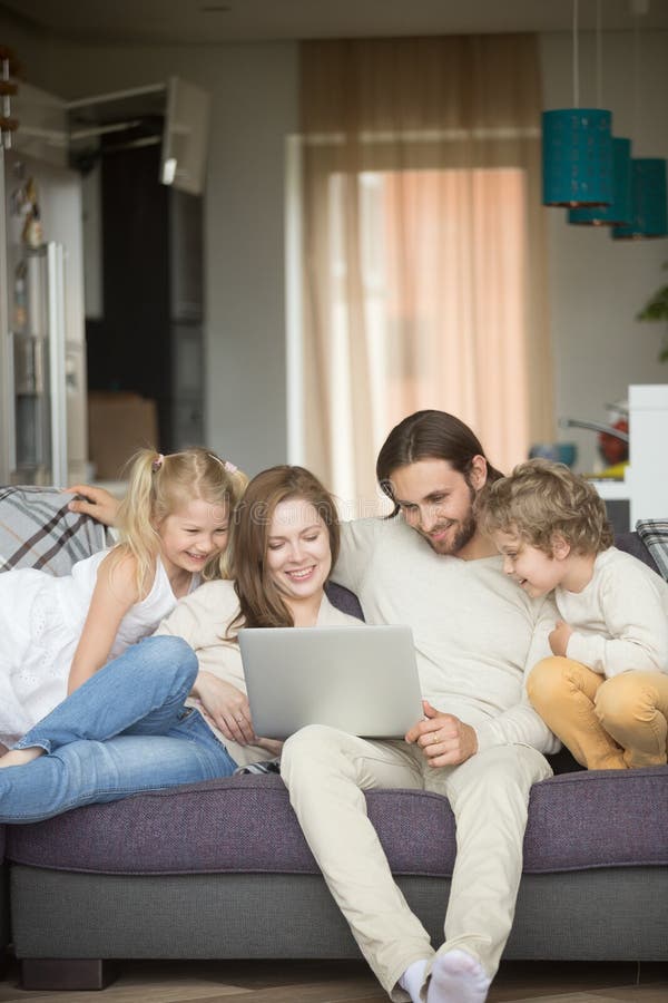 Famille avec des enfants ayant l'amusement utilisant l'ordinateur portable sur le sofa, vertical photographie stock libre de droits Famille avec des enfants ayant l'amusement utilisant l'ordinateur portable sur le sofa, vertical photographie stock libre de droits
