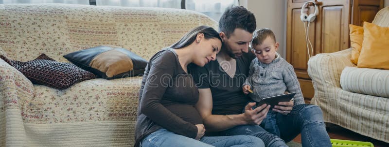 Famille avec l'enfant et la mère enceinte regardant le comprimé photos stock Famille avec l'enfant et la mère enceinte regardant le comprimé photos stock