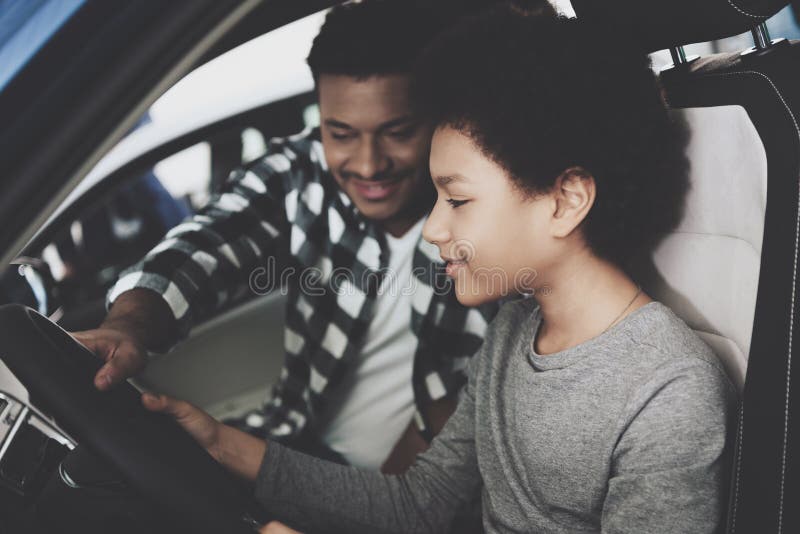 Famille d'afro-américain au concessionnaire automobile Le père et le fils essayent la nouvelle voiture image libre de droits Famille d'afro-américain au concessionnaire automobile Le père et le fils essayent la nouvelle voiture image libre de droits