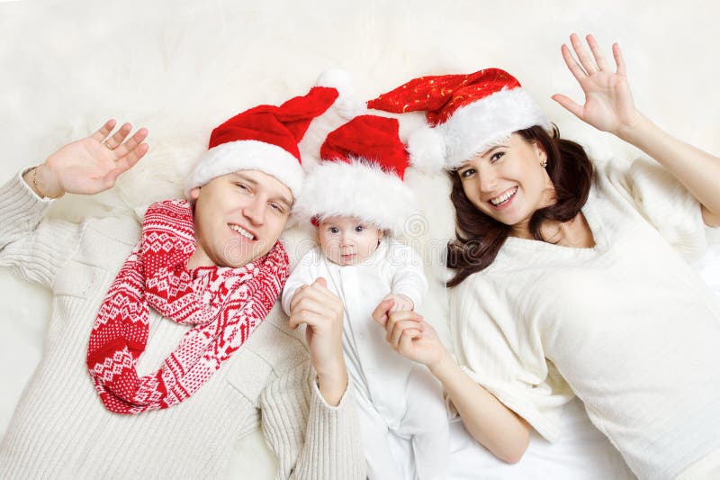 Famille de Noël avec la chéri dans des chapeaux rouges. images libres de droits Famille de Noël avec la chéri dans des chapeaux rouges. images libres de droits