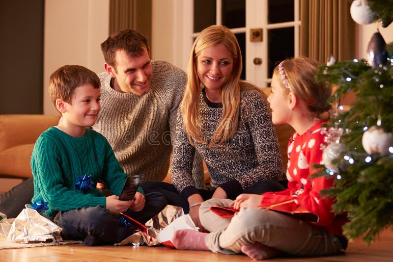 Famille déroulant des cadeaux par l'arbre de Noël photo stock