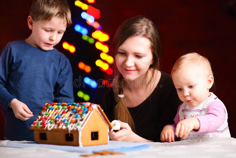 Famille effectuant la maison de pain d'épice photos stock