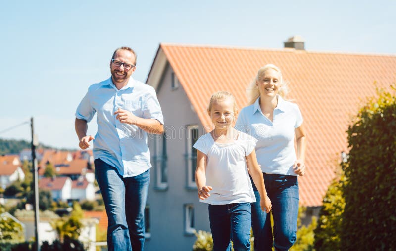 Famille heureuse courant devant leur nouvelle maison image stock Famille heureuse courant devant leur nouvelle maison image stock