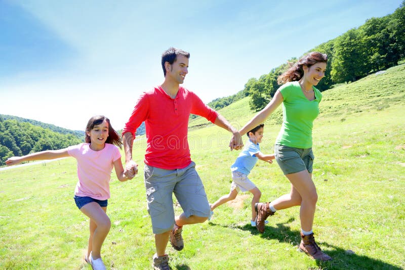 Famille heureuse courant sur la campagne images libres de droits Famille heureuse courant sur la campagne images libres de droits
