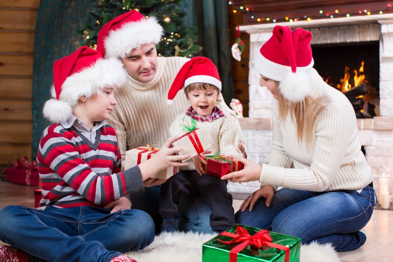 Famille heureuse dans des chapeaux rouges avec des cadeaux photographie stock libre de droits Famille heureuse dans des chapeaux rouges avec des cadeaux photographie stock libre de droits